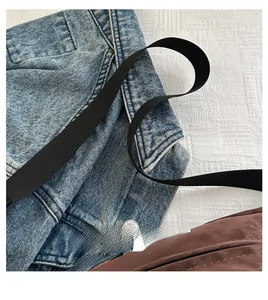 Detail of comfortable wide nylon shoulder strap on a casual washed denim crossbody bag