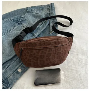 Detailed view of leopard print crossbody bag with adjustable strap on white surface