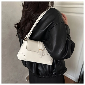 Detail of cream leather underarm bag with gold buckle on a model in a black leather jacket