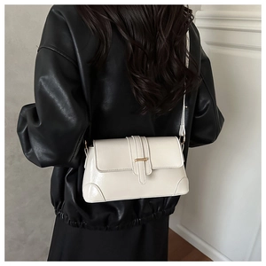 Close-up of white glossy underarm bag with gold metal buckle on a model in leather jacket