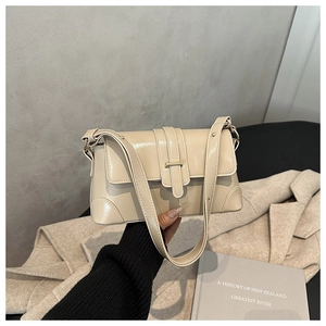 Detail of a beige leather shoulder bag featuring a buckle strap and reinforced corners
