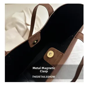 Detail shot of the metal magnetic closure and black interior lining on the brown tote bag