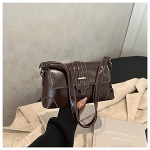 Detail of dark brown leather underarm bag with white stitching and gold hardware