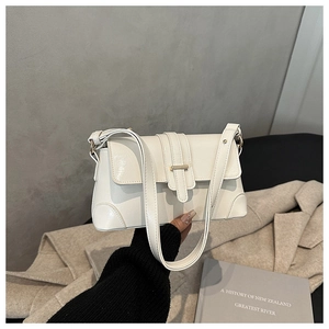 Detail of cream rectangle shoulder bag with gold buckle and reinforced corner guards