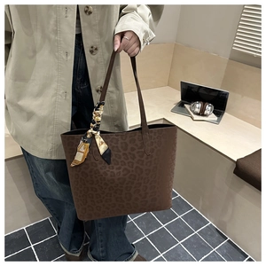 Detail of dark brown leopard print tote bag with elegant silk scarf on slim handles