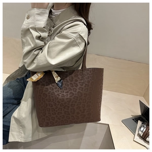 Detail of large brown leopard print tote bag with decorative silk scarf on the shoulder strap