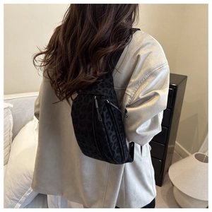 Detailed view of fashionable leopard print crossbody chest bag worn on model's back