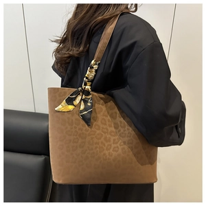 Detail of leopard print suede tote bag with decorative patterned silk scarf on strap