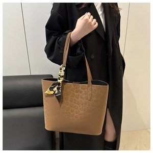 Detail of leopard print suede tote bag featuring a decorative silk scarf on handle
