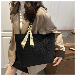 Detail of black leopard print suede tote bag with elegant floral silk scarf on strap
