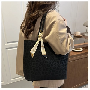 Detail of black leopard print tote bag with a decorative beige printed silk scarf on handle