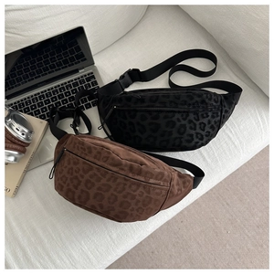 Detailed view of leopard print crossbody waist bags in black and brown on a white sofa