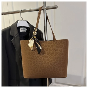 Close-up of leopard print suede tote bag with decorative floral silk scarf on handle
