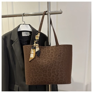 Detail of leopard print suede tote bag with decorative scarf on a display hanger