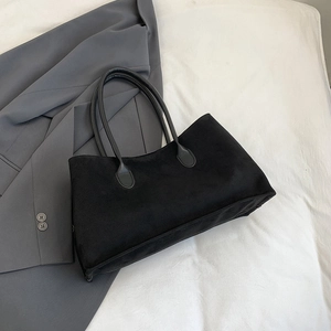 Détail du grand sac cabas noir mat posé sur un blazer gris professionnel élégant