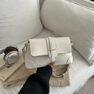 Chic vintage French-style cream baguette bag with gold metal buckle on white sofa