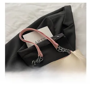 Detail of cream tote bag with pink leather handles and silver chain links