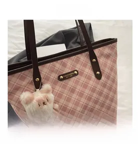 Detail of pink plaid tote bag featuring brown leather handles and a cute teddy bear charm