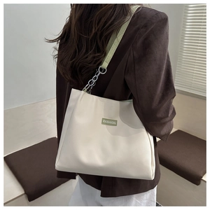Detail of off-white tote bag with light green leather strap and silver chain accent