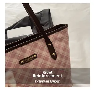 Detail of plaid tote bag with gold rivets reinforcement and leather handles