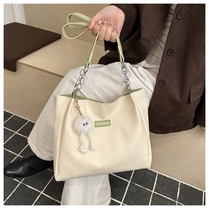 Detail of off-white PU tote bag with green FASHION text and plush monster charm