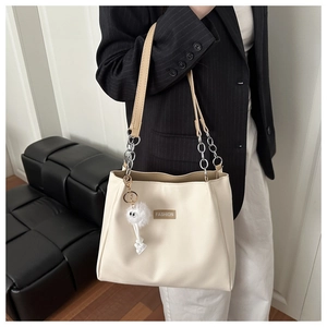 Detail of off-white tote bag with brown leather straps and silver chain attachments