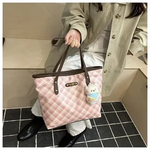 Detail of pink plaid tote bag with brown leather strap and cute white bear charm