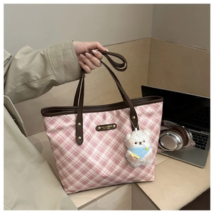 Macro shot of pink checkered tote bag with leather straps and cute bear pendant