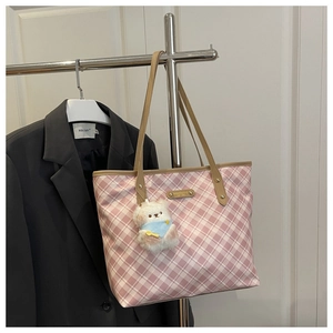 Detail of pink plaid tote bag with brown leather handles and a cute bear keychain charm