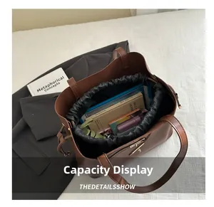 Brown leather tote with a black drawstring liner showing large capacity for laptop and books