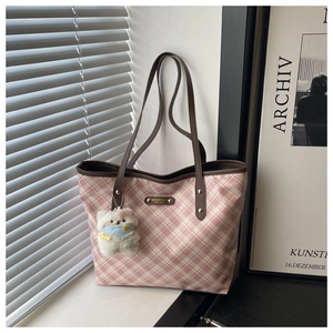 Detail of pink and white checkered tote bag with brown straps and a plush bear charm