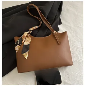 Detailed view of brown PU tote bag with silk scarf handle and size comparison to a phone