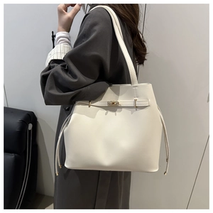 Detail view of cream white bucket bag with gold metallic buckle and drawstring texture