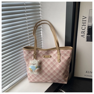 Close-up of pink checkered tote bag with brown straps and a cute white teddy bear charm