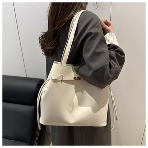 Detail view of a cream-white bucket tote bag with drawstring and shoulder strap on model