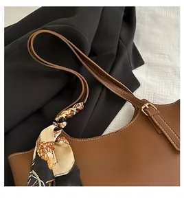 Brown leather tote detail with contrasting stitching and a silk scarf wrapped on the handle