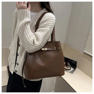 Detail showing high-quality lychee texture leather and classic metal buckle on a brown tote