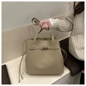 Detail view of khaki bucket tote bag featuring golden twist-lock closure and leather texture