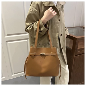 Detailed close-up of a caramel leather bucket bag with metal buckle and drawstring side