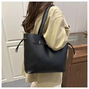 Detail of black large tote bag with decorative drawstrings and gold buckle adjustment