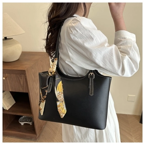 Detail of black leather tote bag with printed silk scarf handle and gold buckle