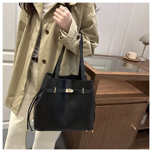 Detail of black leather bucket bag with gold clasp and drawstring in a lifestyle setting