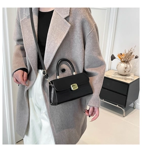 Minimalist black leather mini square bag with gold buckle on a wool coat outfit