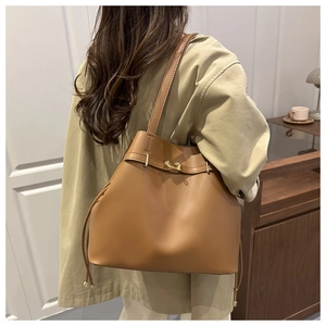 Close-up of caramel leather bucket bag featuring a gold metal twist lock and drawstring detail