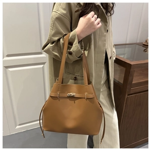 Close-up of brown PU leather bucket bag with gold clasp shown on a shoulder