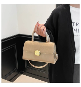 Close-up of beige suede and leather handbag with gold magnetic buckle and top handle