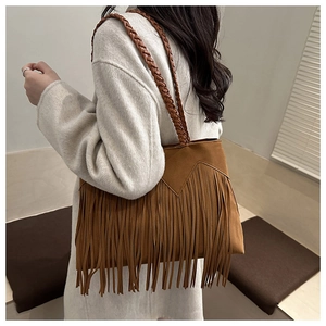 Détail d'un sac cabas en daim marron avec des franges denses et des anses tressées