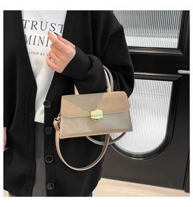 Detail of a beige square handbag with a golden metal buckle and versatile shoulder strap