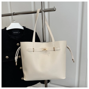 Detailed view of cream-white leather tote bag with gold metal buckle and drawstring side