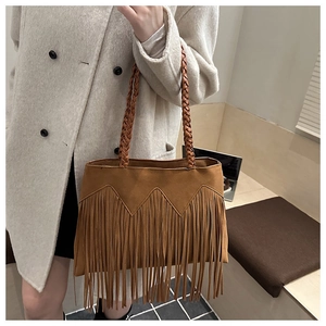 Détail d'un sac bohème avec poignées tressées et longues franges en daim marron